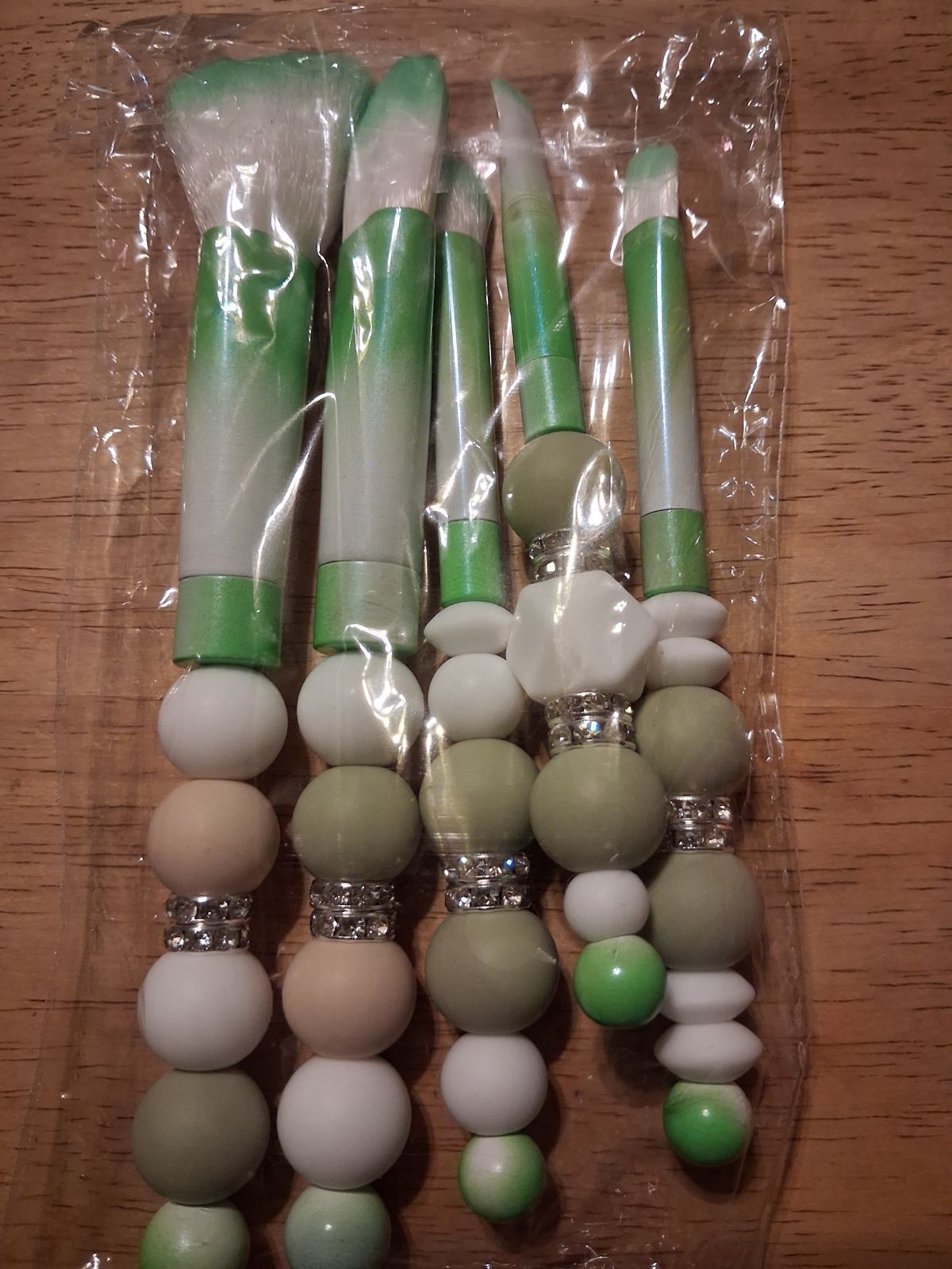 Makeup brushes with green and white beaded handles and sparkling spacers
