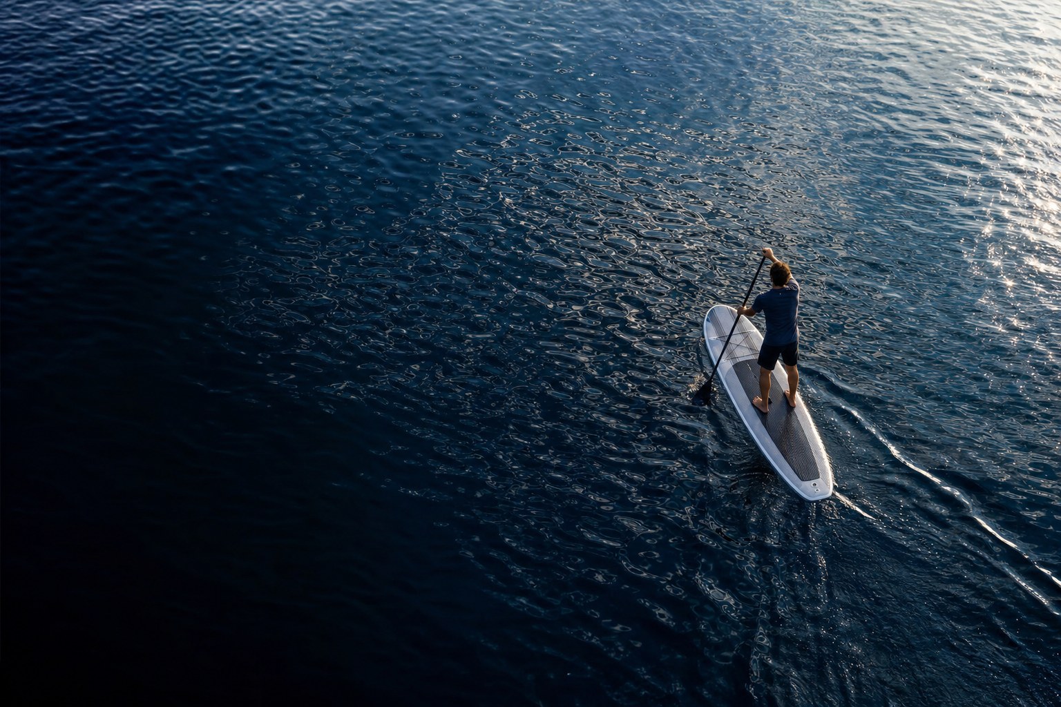 Paddleboarder crossing deep blue water