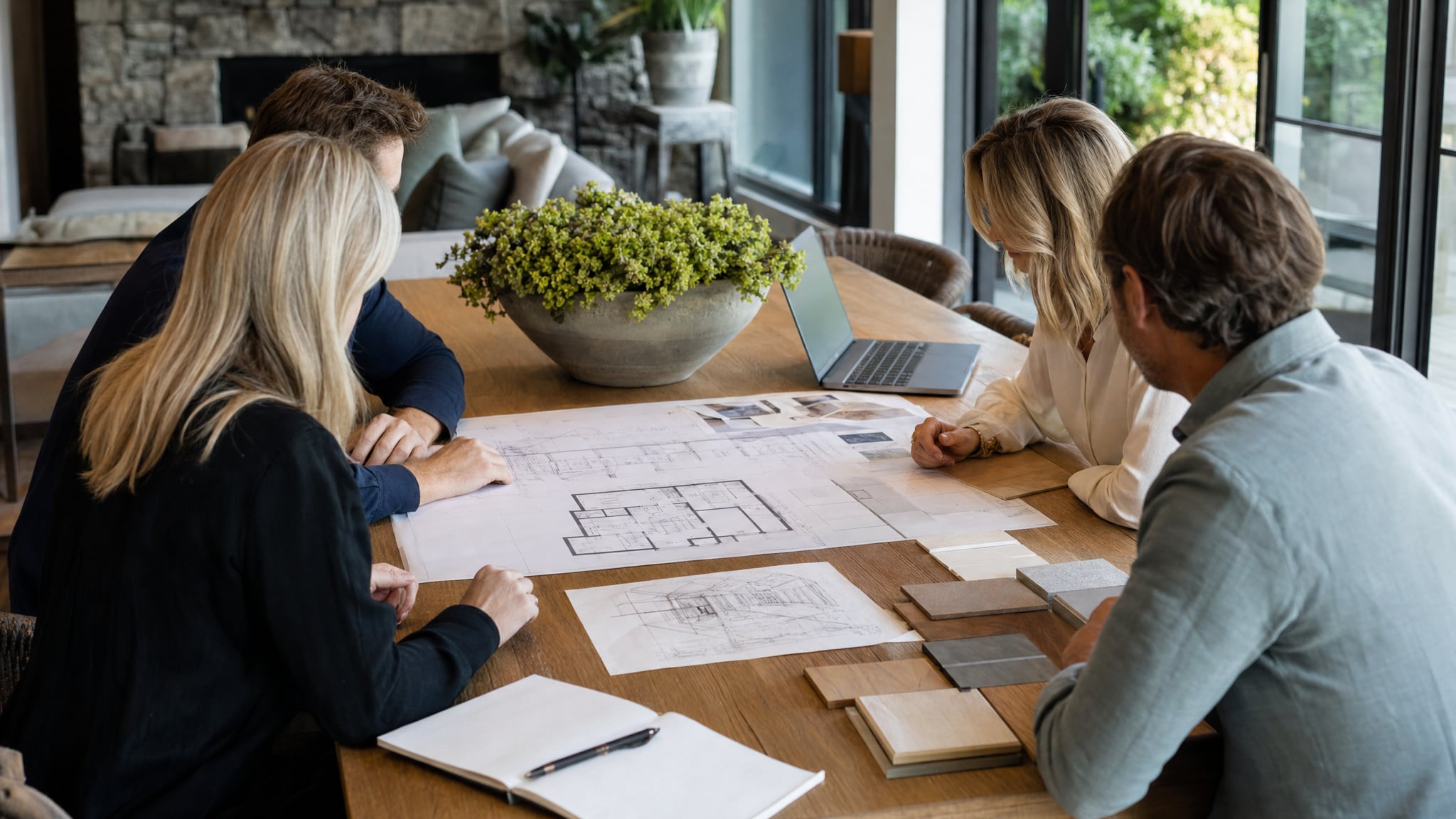 Homeowners, an architect, and an interior designer reviewing house plans and material samples