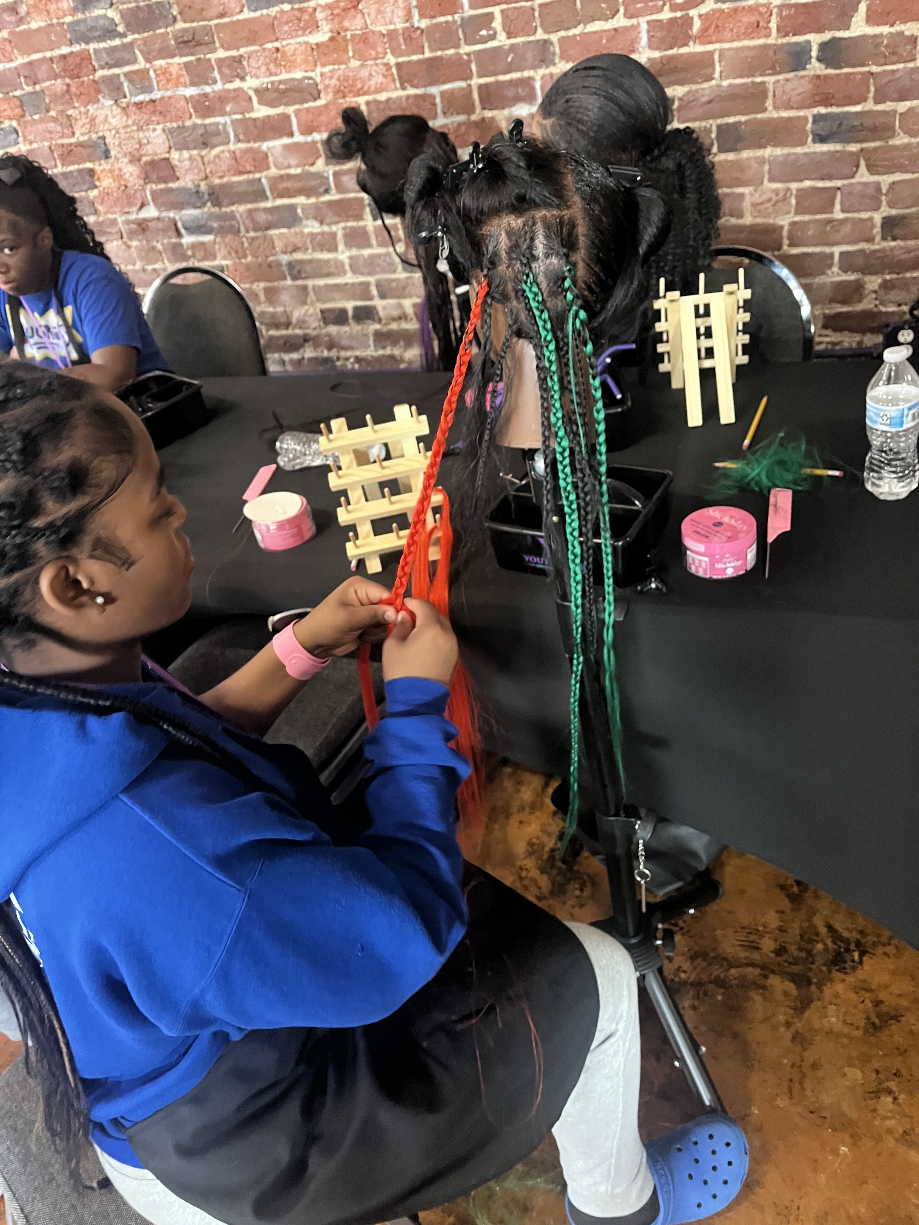 Youth Braid and Business Academy student practicing braiding on a mannequin