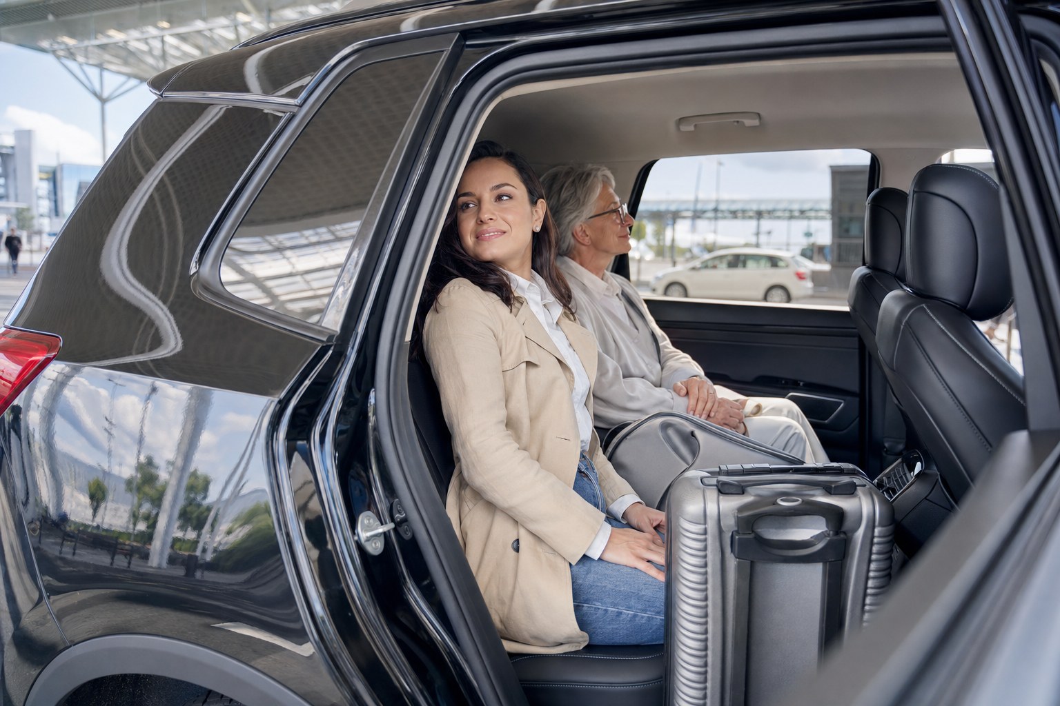 Traveler and older companion seated in an SUV with luggage after an airport pickup