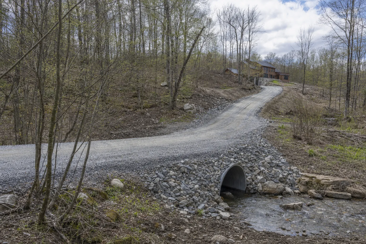 A gravel Vermont driveway crossing a culvert and climbing through a wooded property