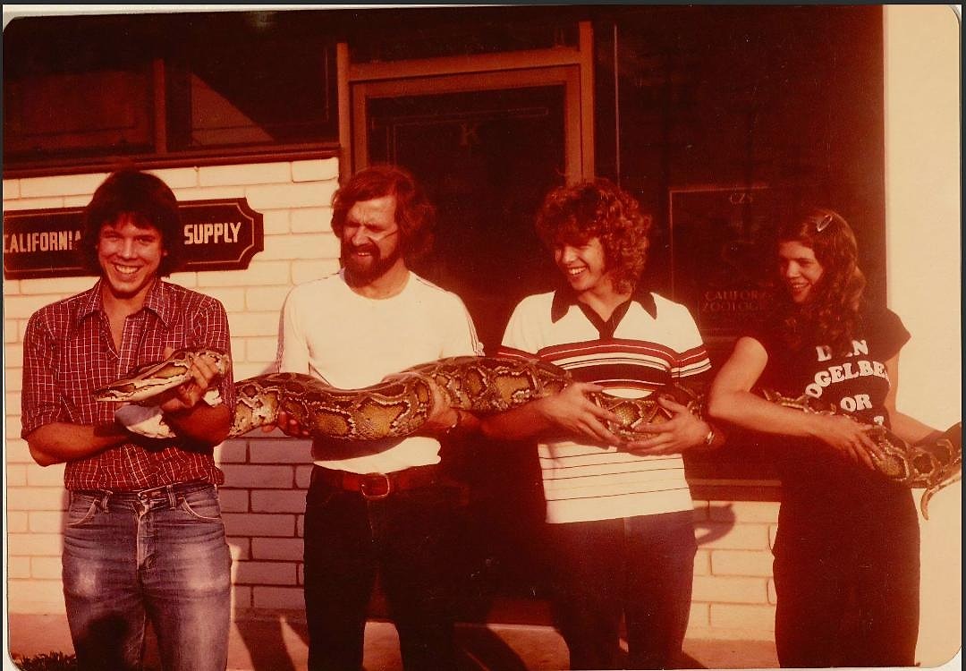 Historic California Zoological Supply photo of four people holding a large snake outside the business