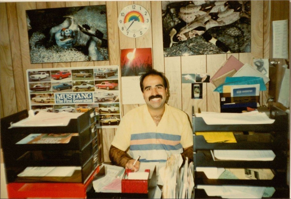Historic Cal Zoo office photo of a man seated at a desk surrounded by paperwork and reptile photographs