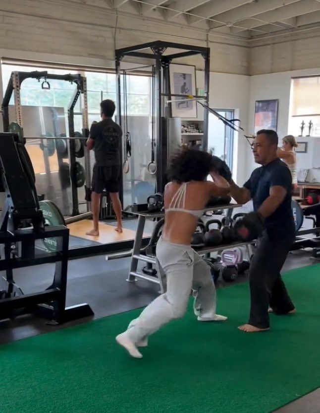 Vinny Cruz coaching a client with focus mitts in the gym