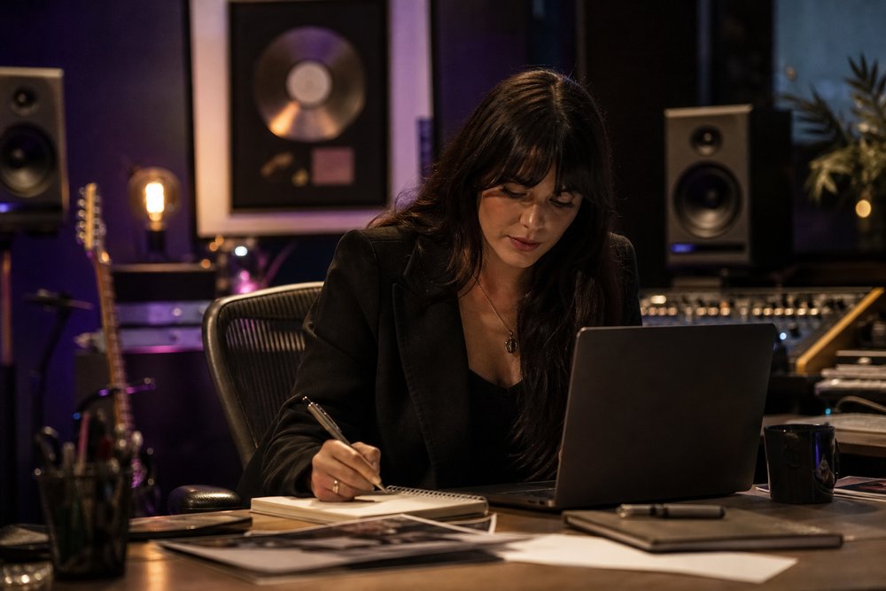 Close-up of a publicist writing a press release on a laptop with a notebook and pen