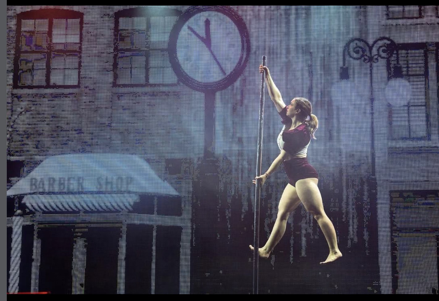 Kristy Sellars performing on pole before a giant clock