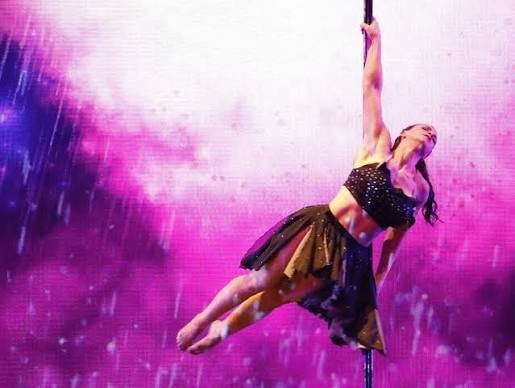 Kristy Sellars performing on pole in pink light