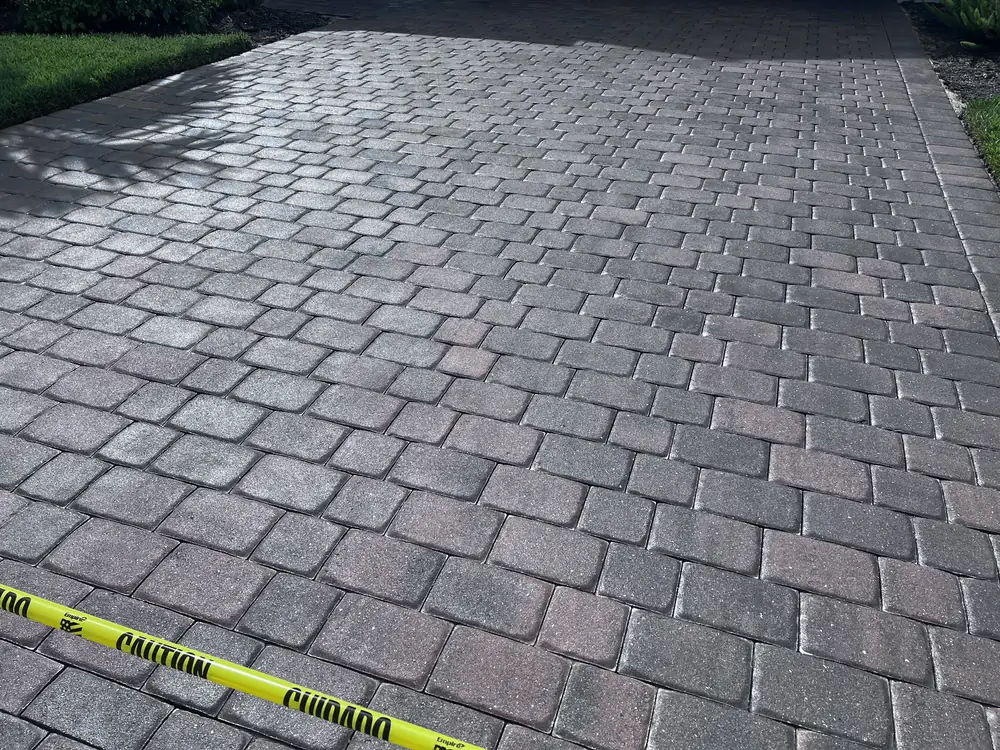 Freshly sealed paver driveway curing behind yellow caution tape in Estero, FL