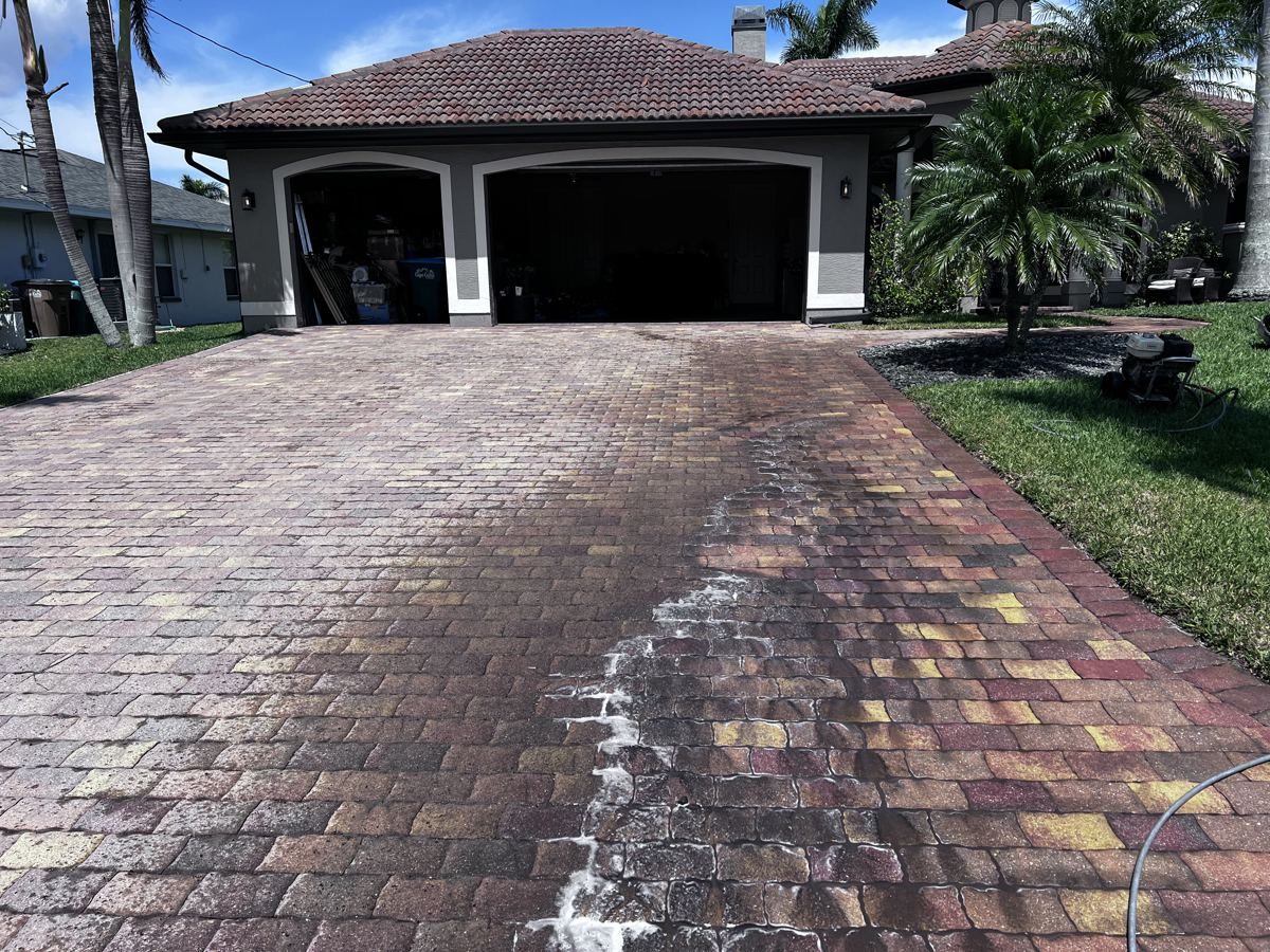 Paver driveway partway through cleaning, with a clear line between dull pavers and restored color, in Cape Coral, FL