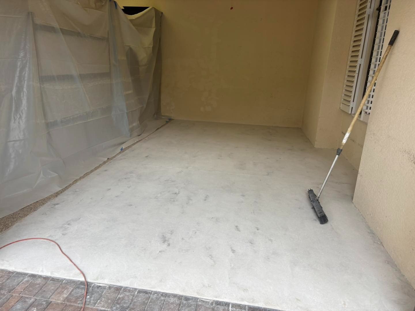 Bare garage floor beside a roller and protective wall covering