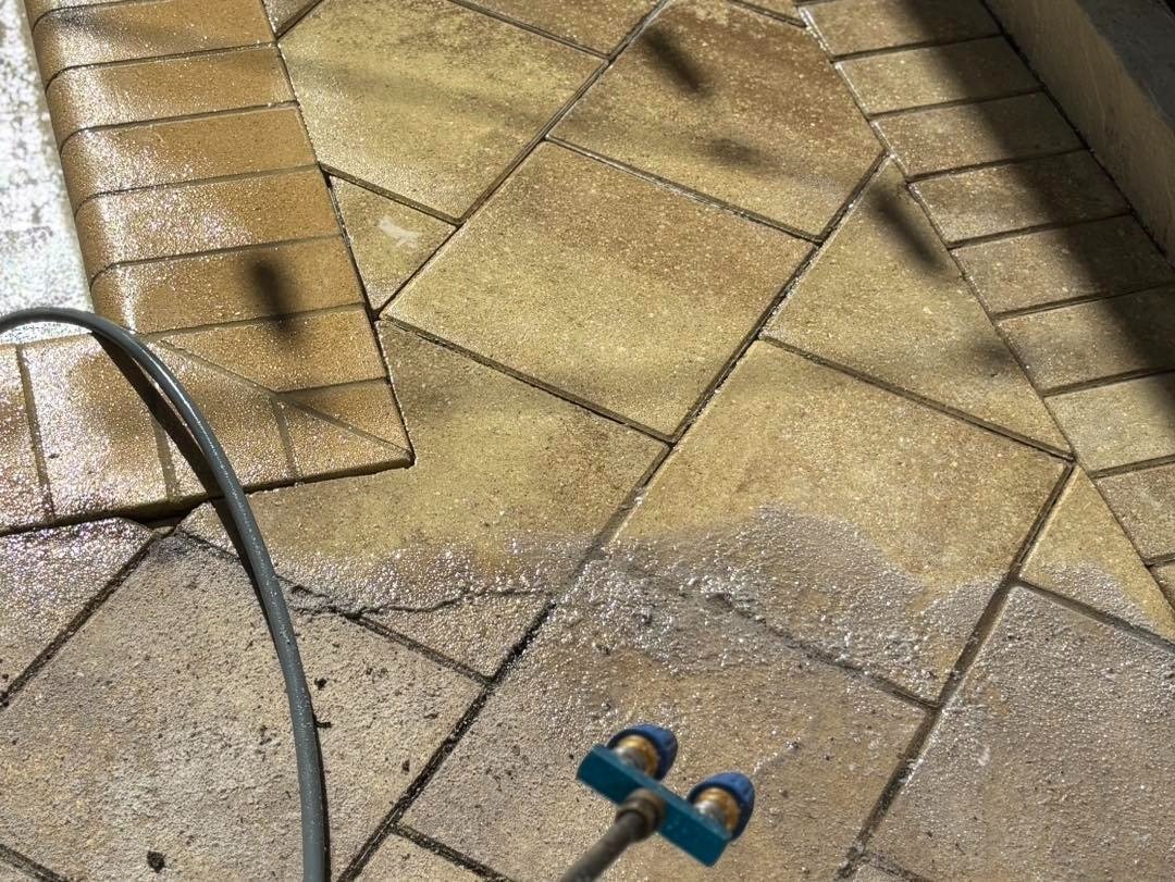 Brown patterned paving beside a hose and blue handled tool