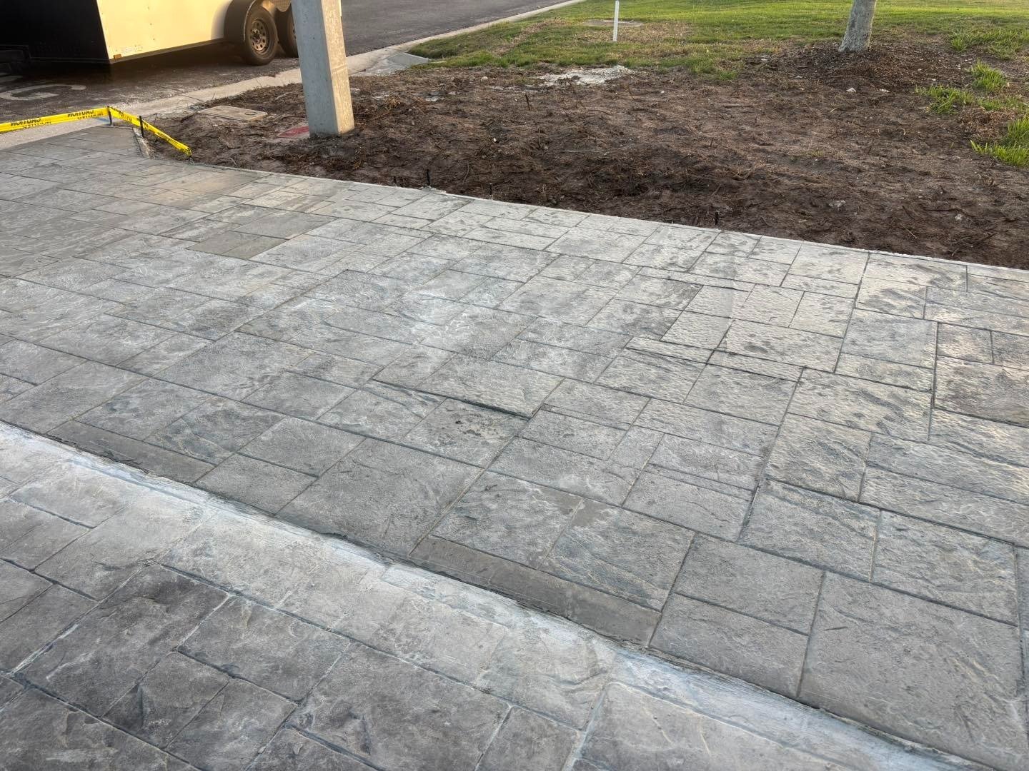 Close view of a pale patterned driveway beside a bare planting bed