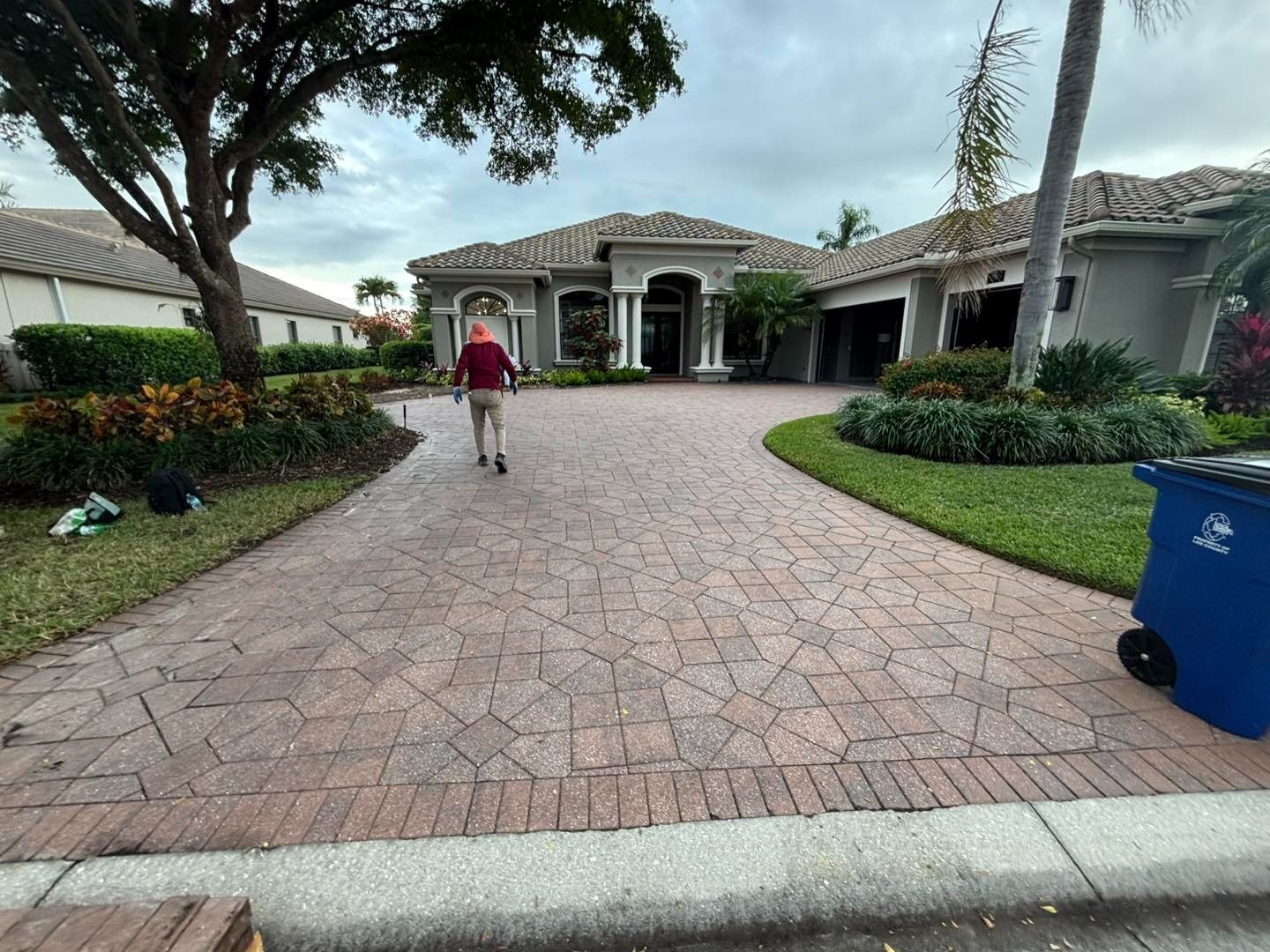 Curved patterned driveway outside a house with a blue recycling bin
