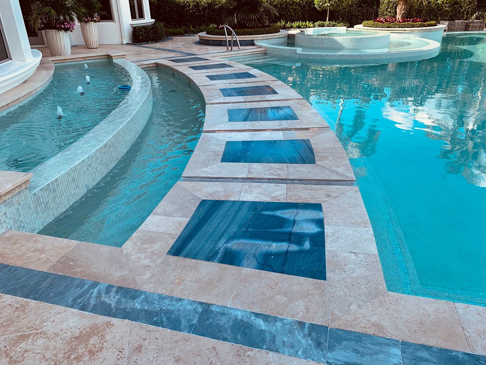 Curved pool ledge with square blue tile accents beside a raised spa