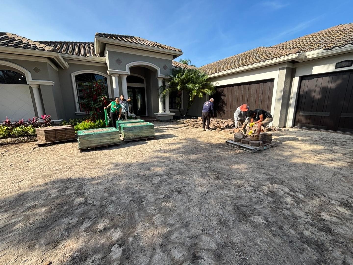 Driveway work area with workers and equipment outside a home