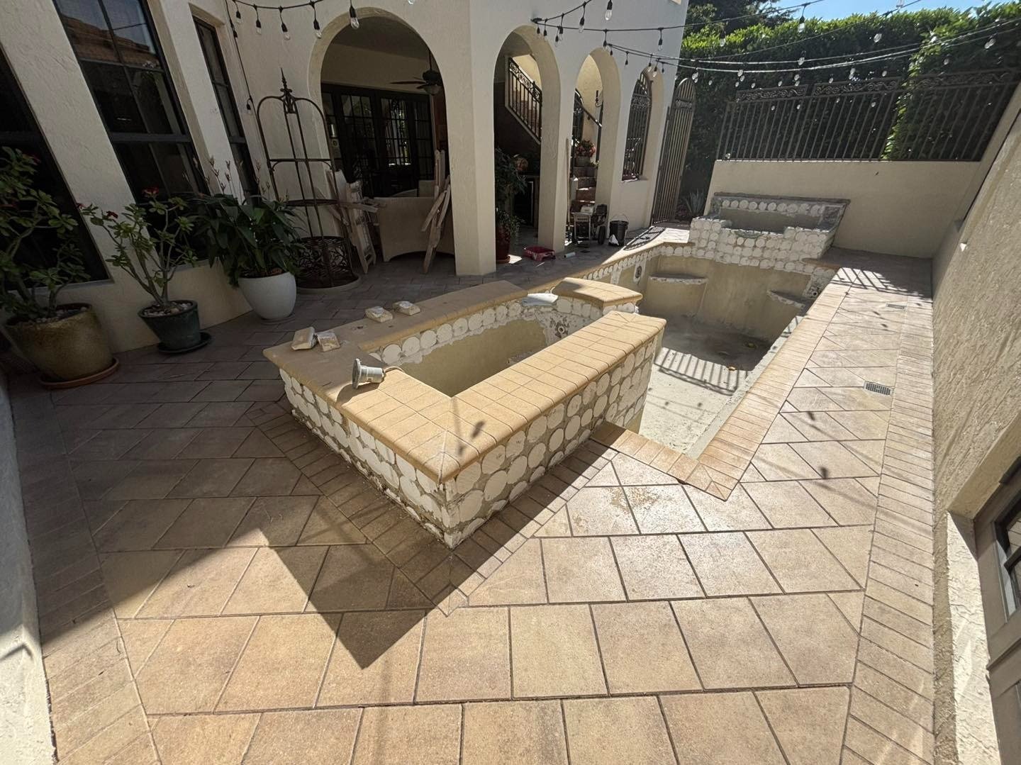 Empty courtyard pool and raised spa surrounded by patterned paving