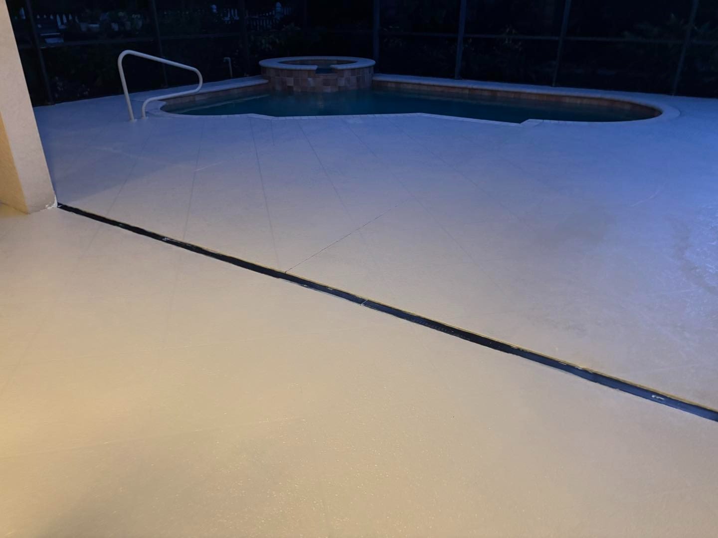 Evening view of pale pool decking with dark joints and curved pool edge