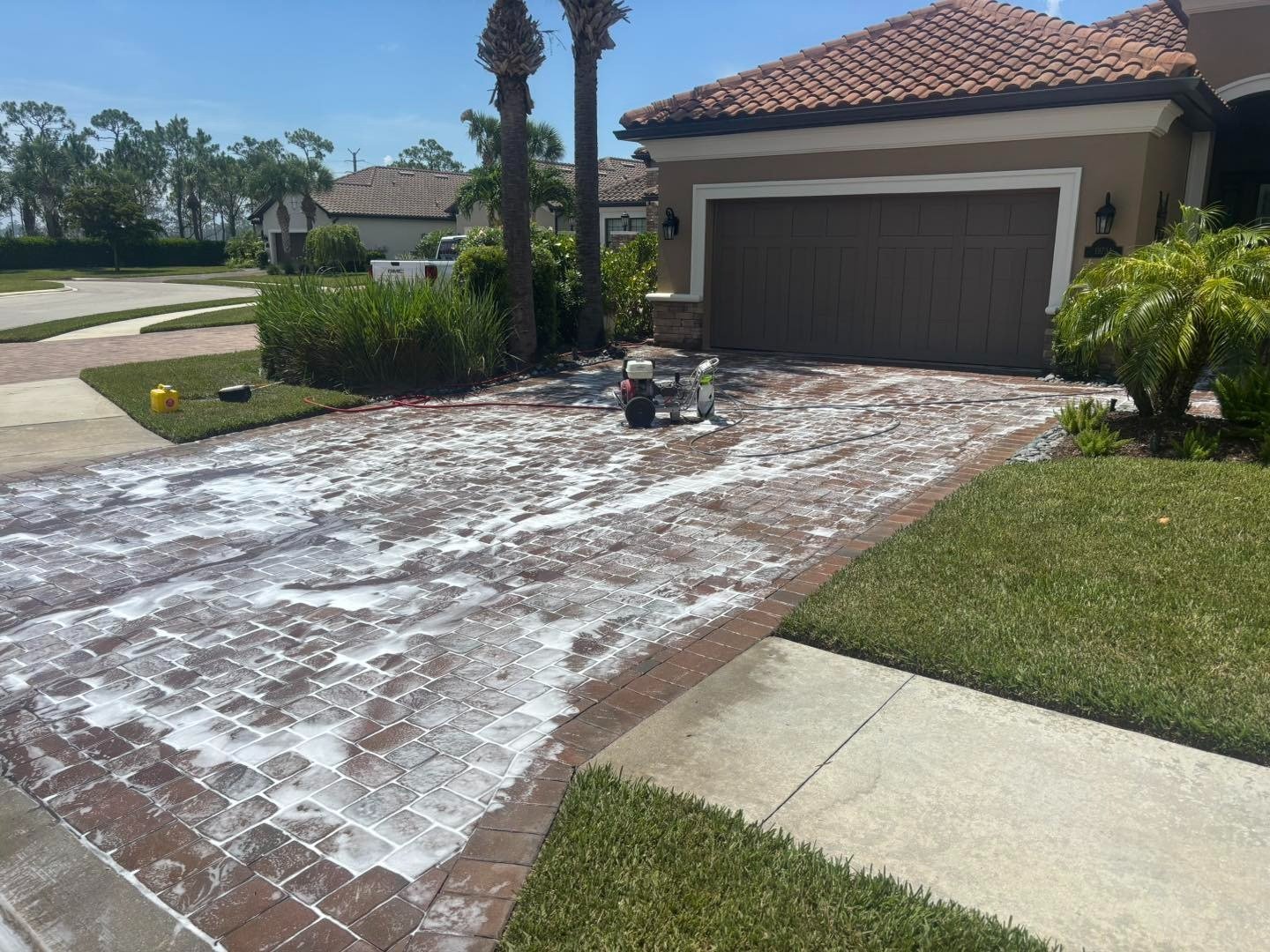 Foam-covered paver driveway outside a house with a dark double garage
