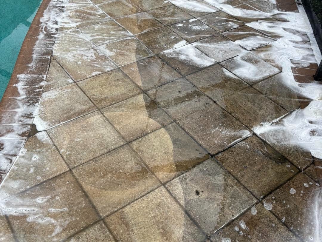 White foam on square pool deck tiles with dark patches and joints