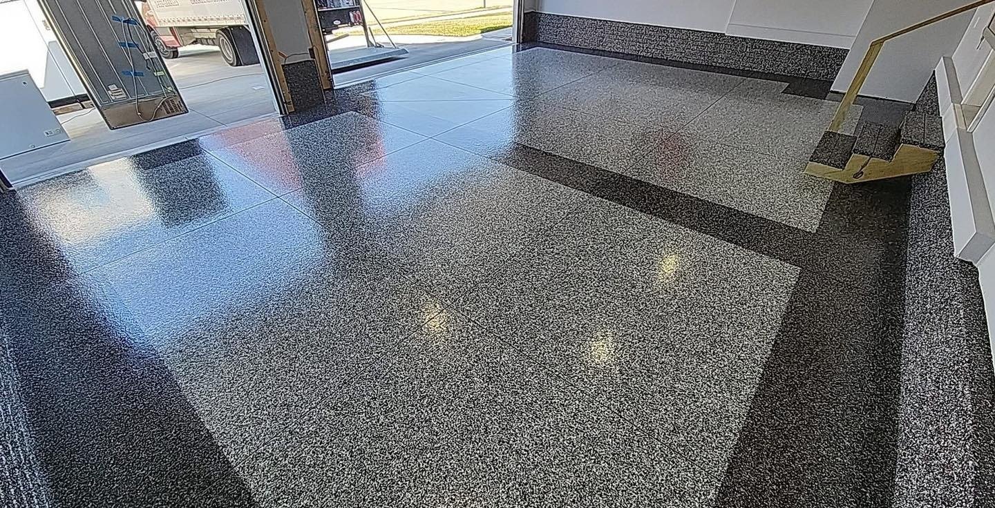 Glossy speckled garage floor with dark borders beside steps and an open entrance