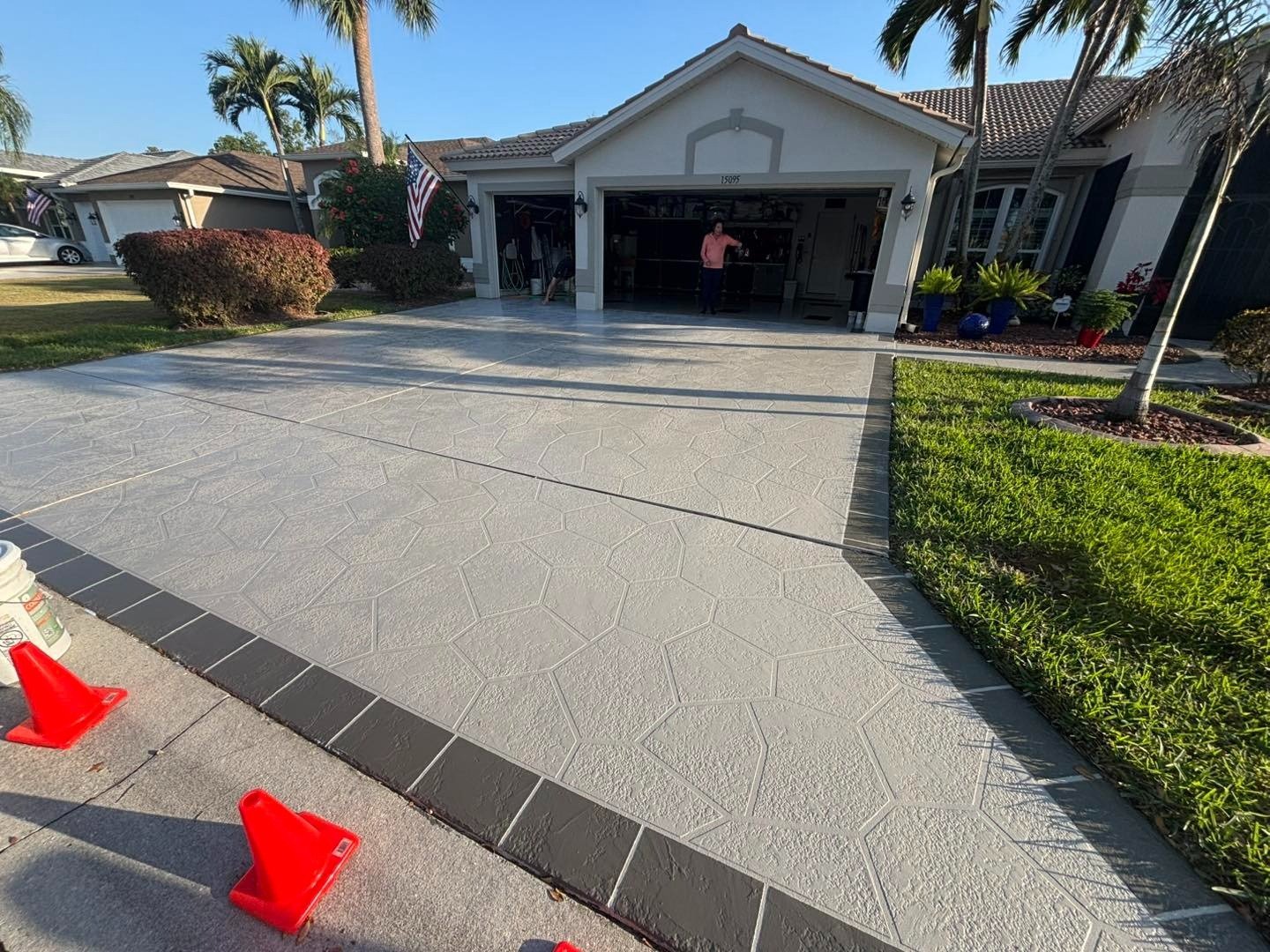 Light gray patterned driveway with dark border and orange cones