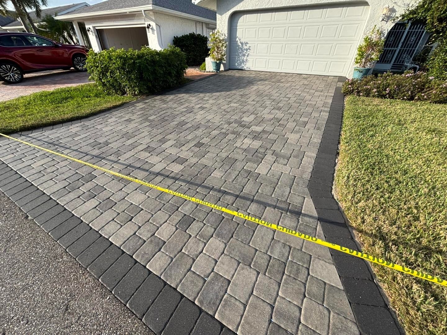 Gray paver driveway with dark border blocked by yellow caution tape