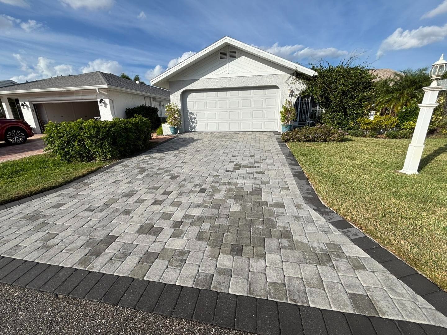 Gray paver driveway leading uphill to a white garage door