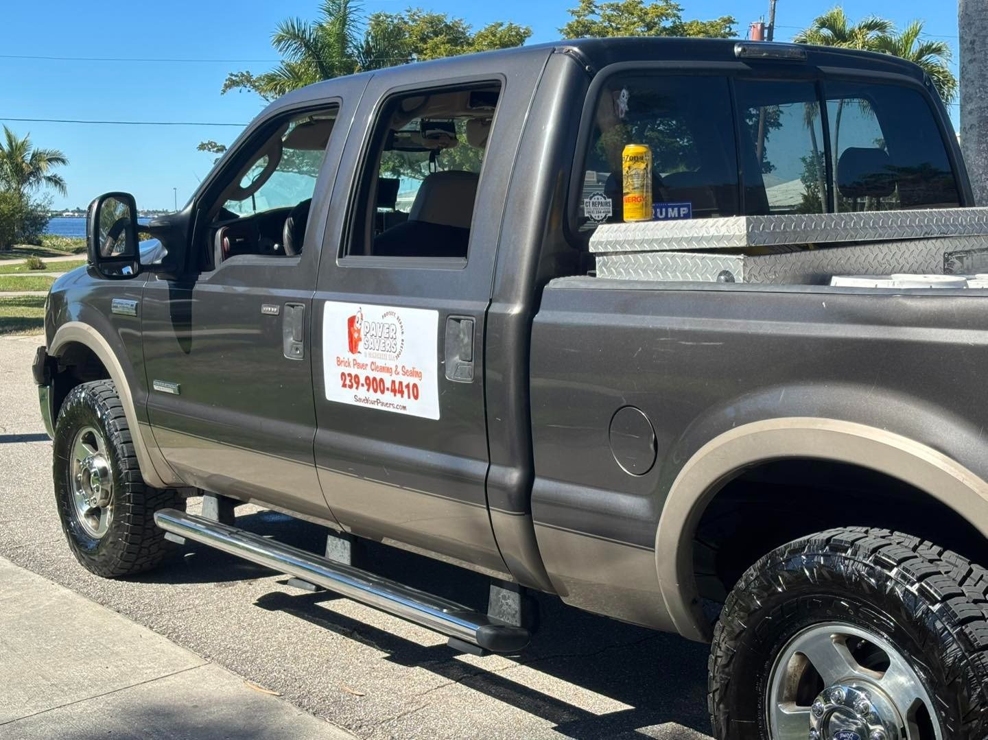 Gray work pickup truck with company signage parked beside pavers