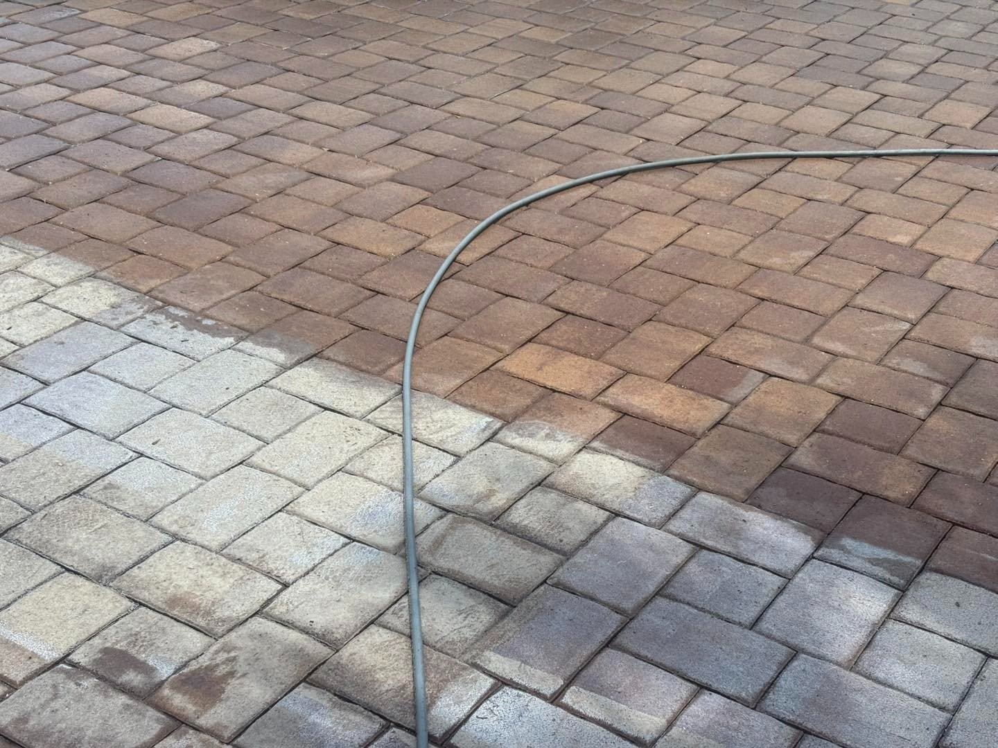 Hose crossing brown and gray pavers with a visible change in surface color