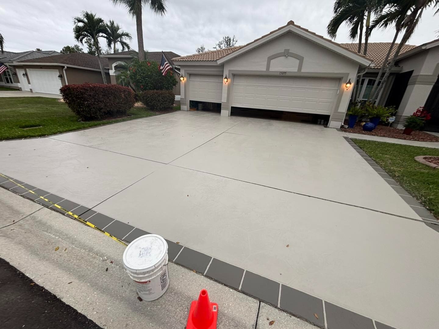 Light gray driveway with dark border outside a white garage