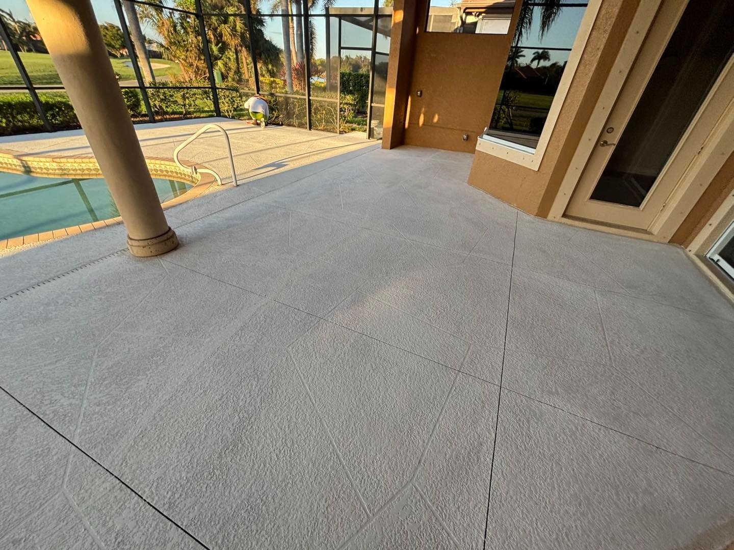 Light gray patio floor beside a swimming pool and sliding doors