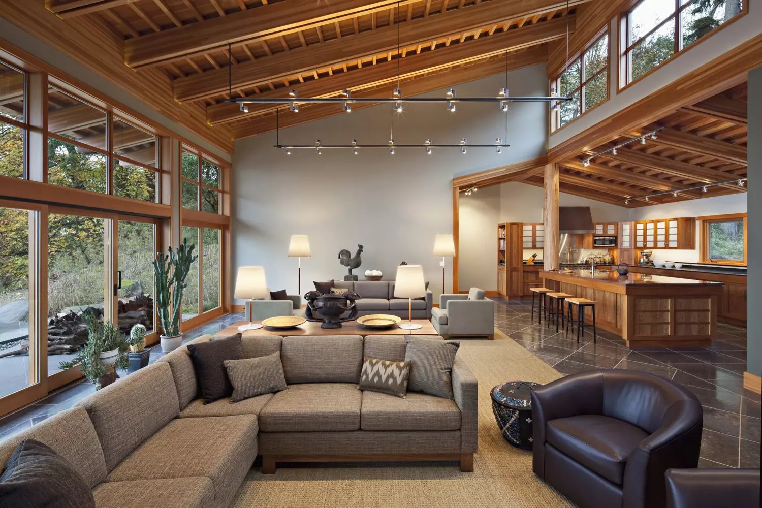 Open living room and kitchen with exposed wood beams and dark tiled floors