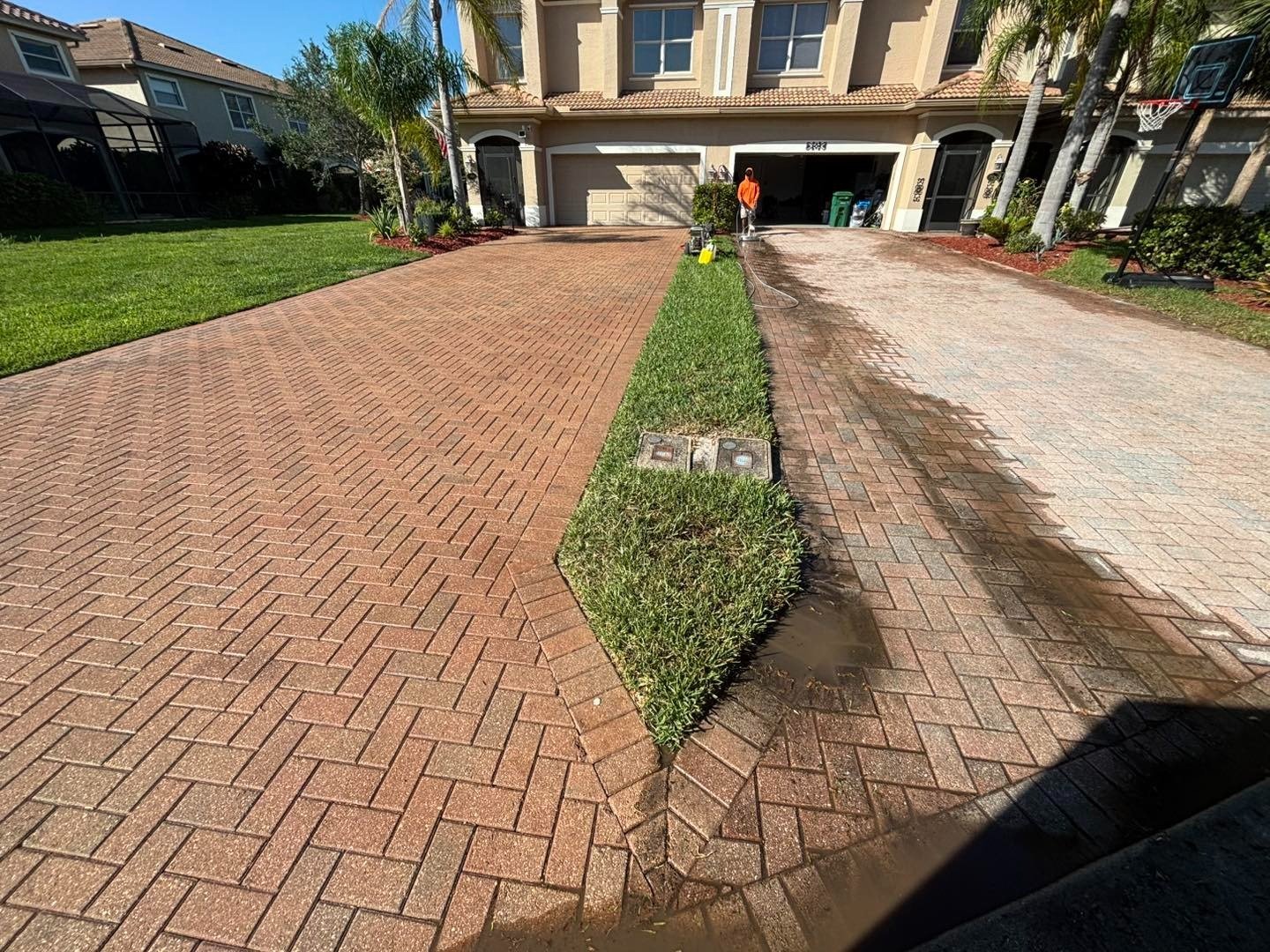 Long red herringbone paver driveway beside a narrow planted divider
