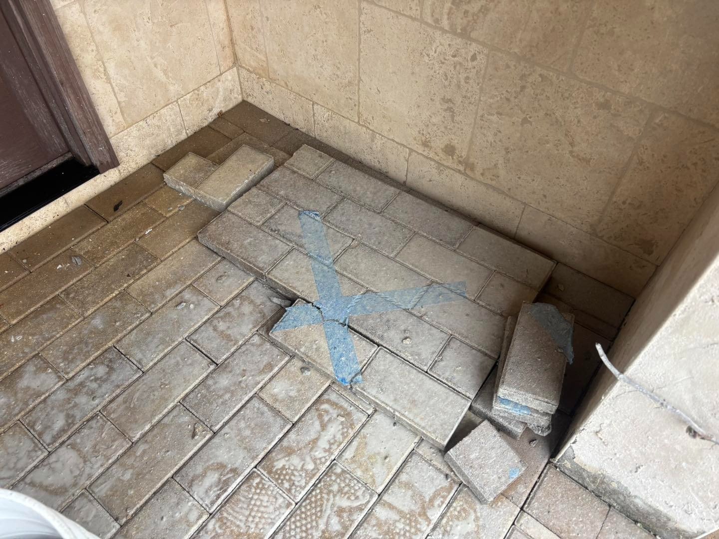 Loose rectangular pavers beside exposed base at a sheltered front doorway