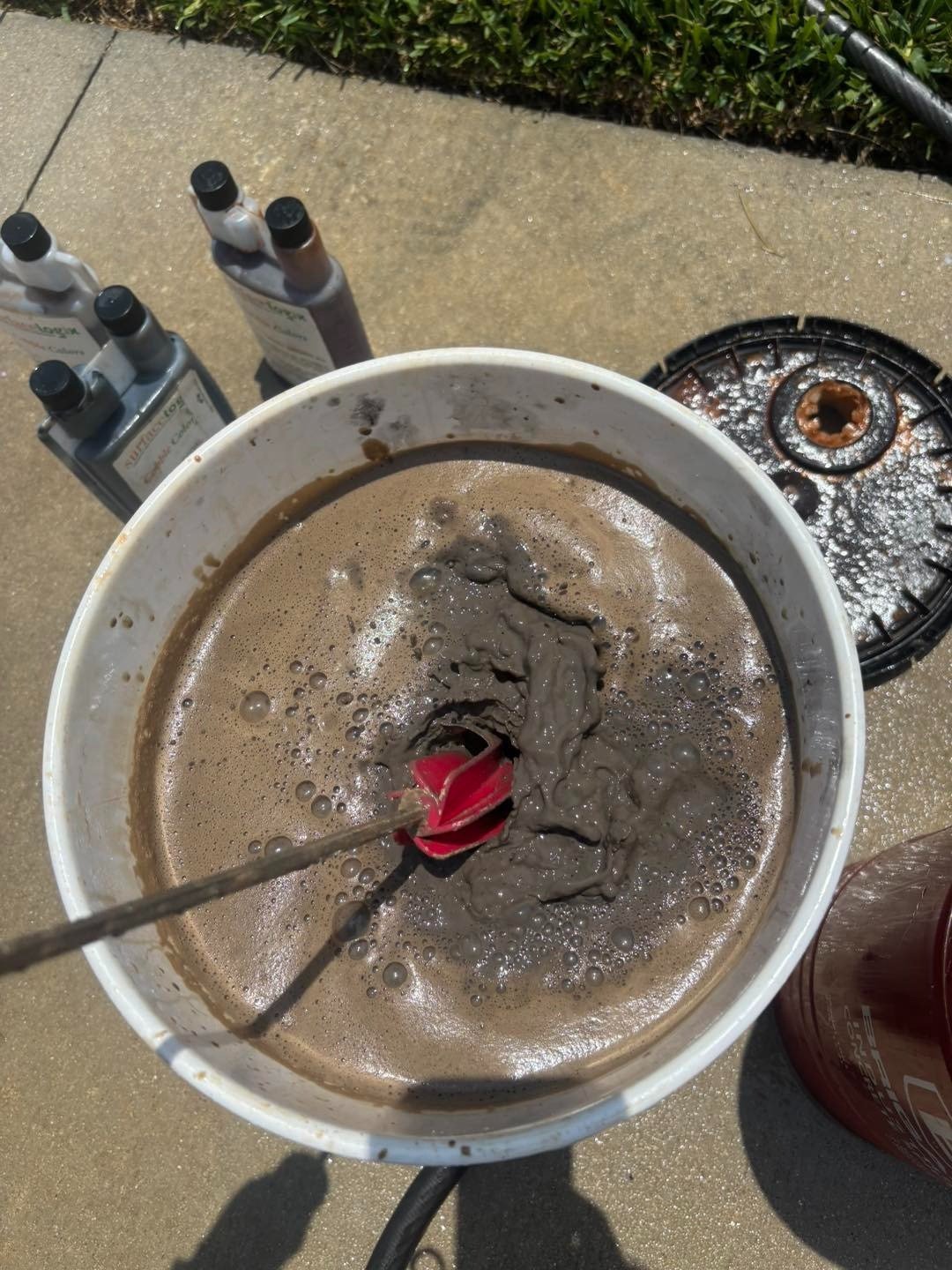 Mixing paddle and gray mixture in a bucket beside work supplies