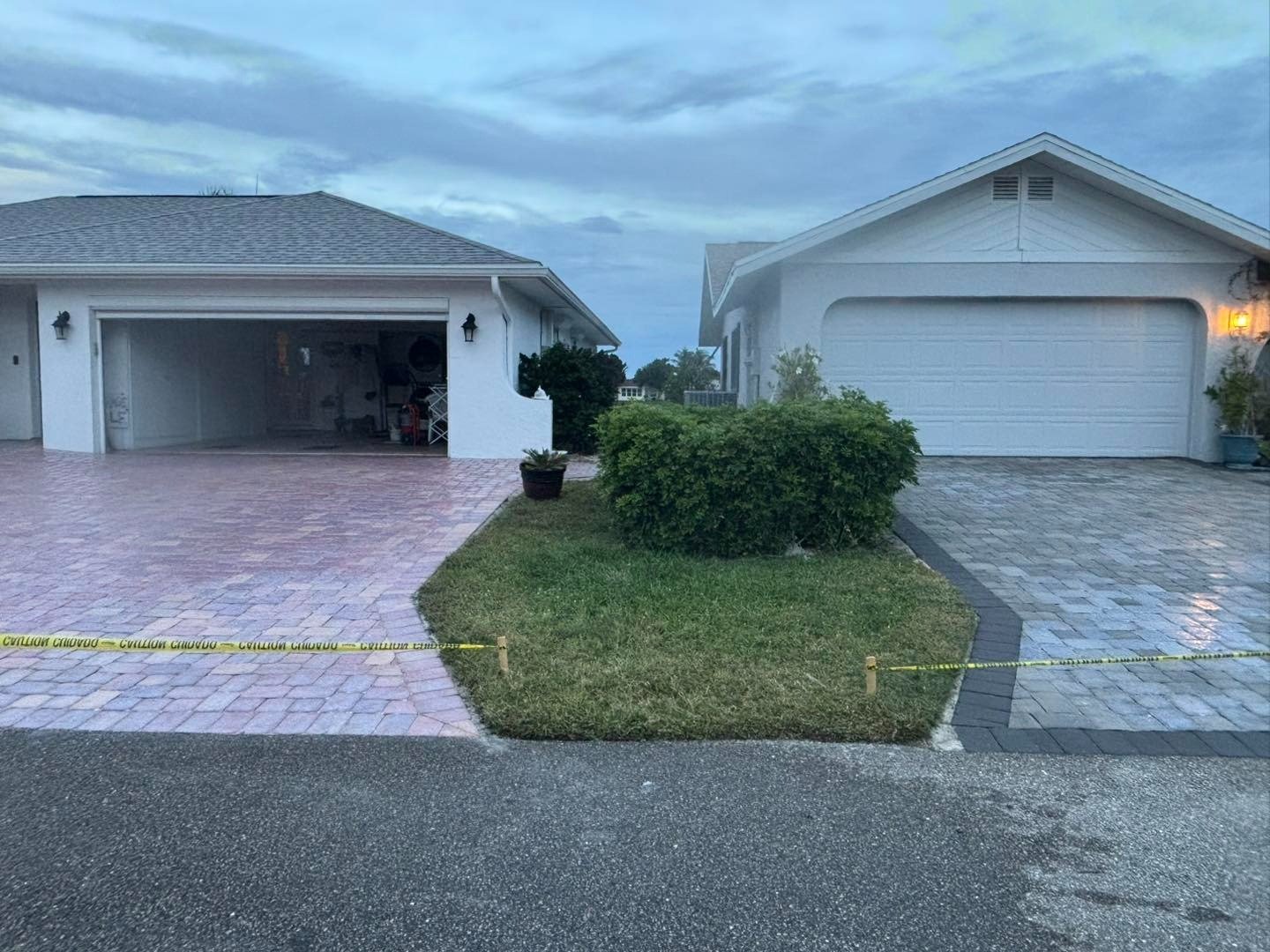 Neighboring pale paver driveways with caution tape across one entrance