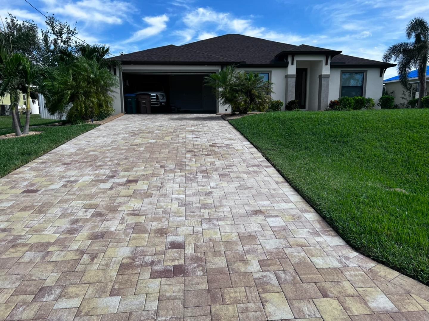 Pale multicolored paver driveway leading to an open double garage