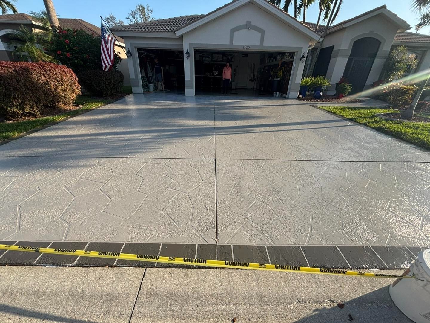 Pale patterned driveway with caution tape across the entrance outside an open garage