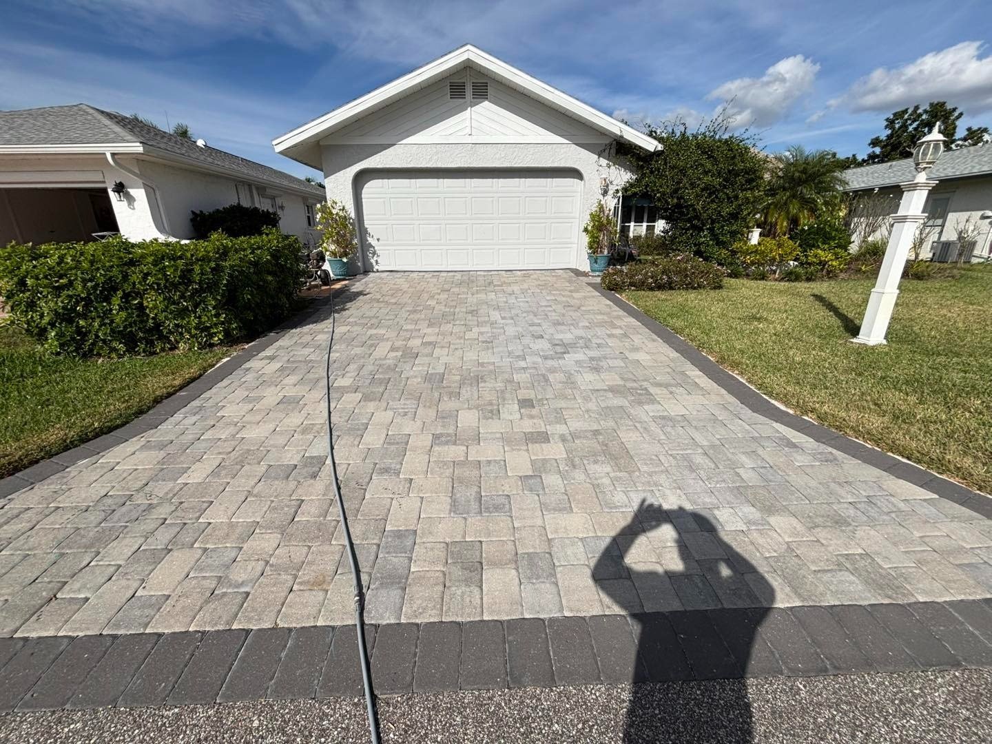 Pale paver driveway with dark border and photographer shadow