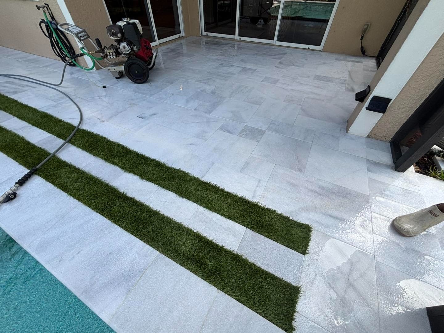 Pale poolside patio with narrow grass strips and washing equipment