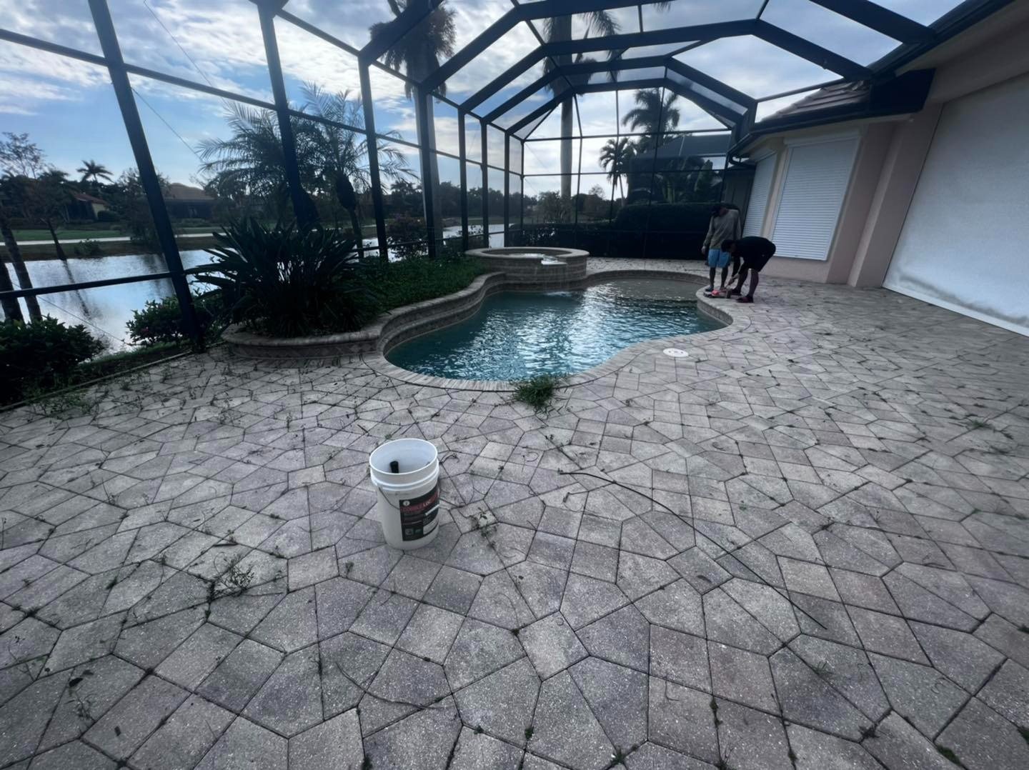 Patterned pool deck inside a screened enclosure beside a lake