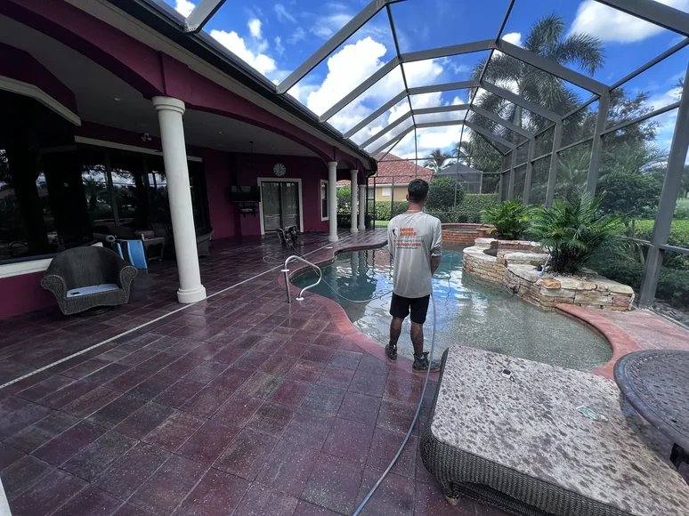Freshly sealed brick paver pool deck around a pool and spa inside a screened lanai in Bonita Springs, FL