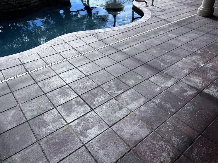 Close-up of hazy, whitened failed sealer on pool deck pavers in Bonita Springs, FL, before stripping