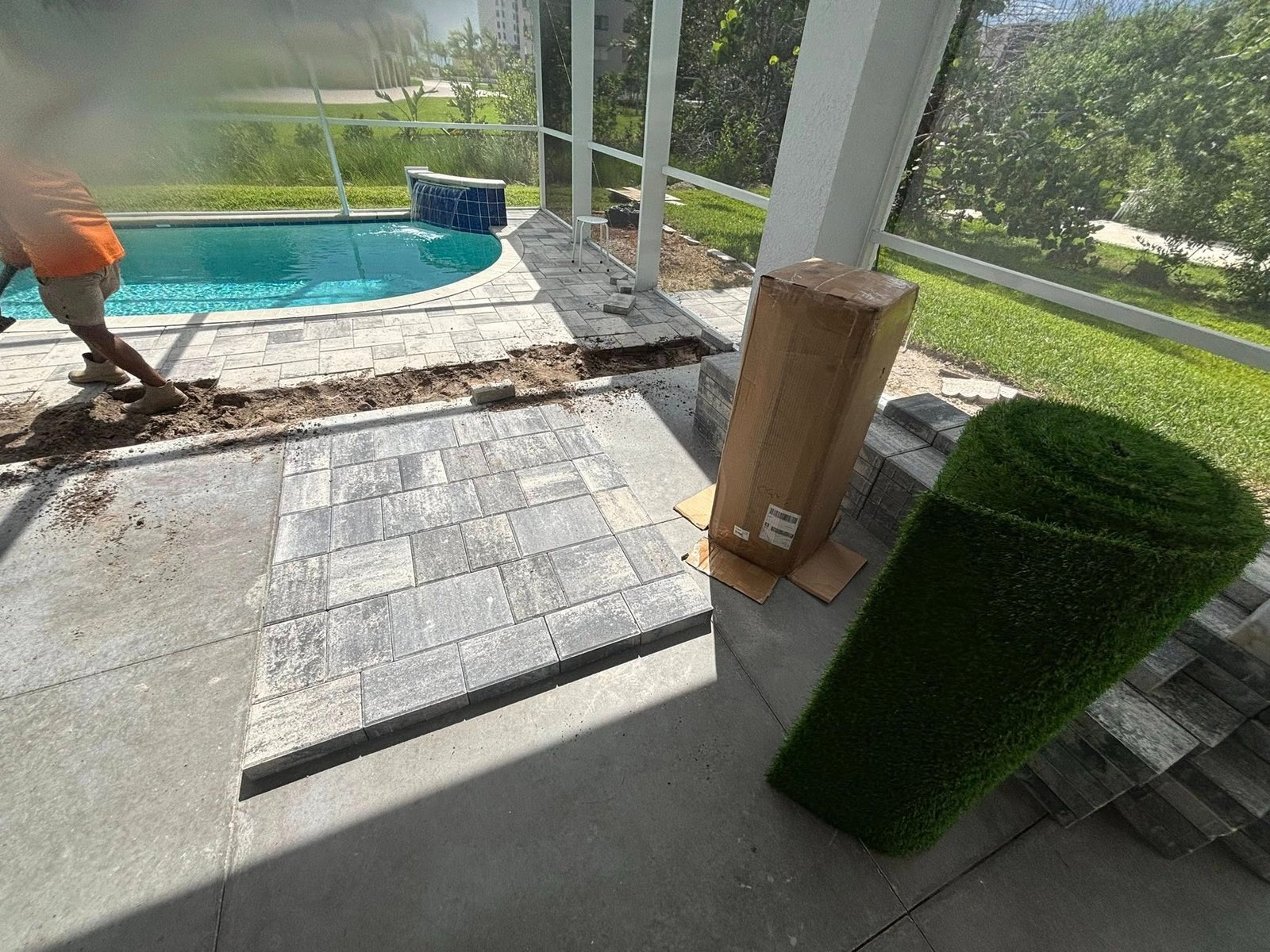 Pavers and exposed base beside a patio column and screened pool enclosure