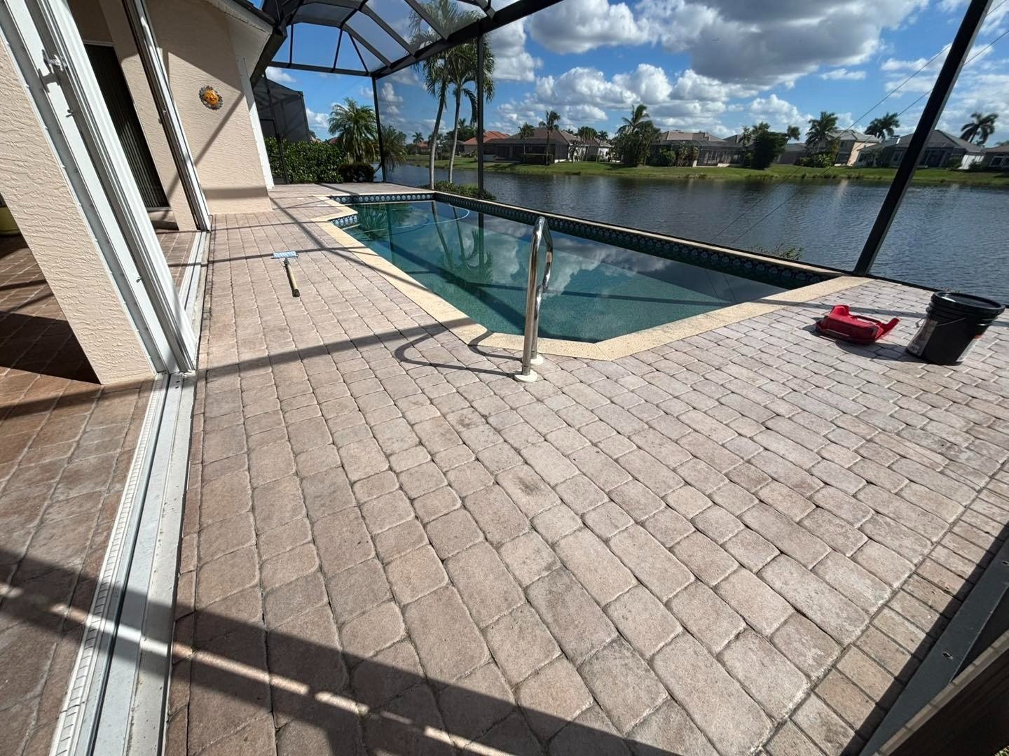 Rectangular paver deck beside a screened pool overlooking a lake