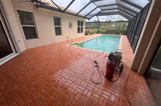 Red patterned pool deck beside a house inside a screened enclosure