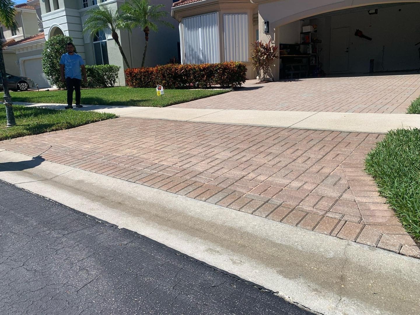 Reddish driveway pavers meeting a pale concrete strip near the street
