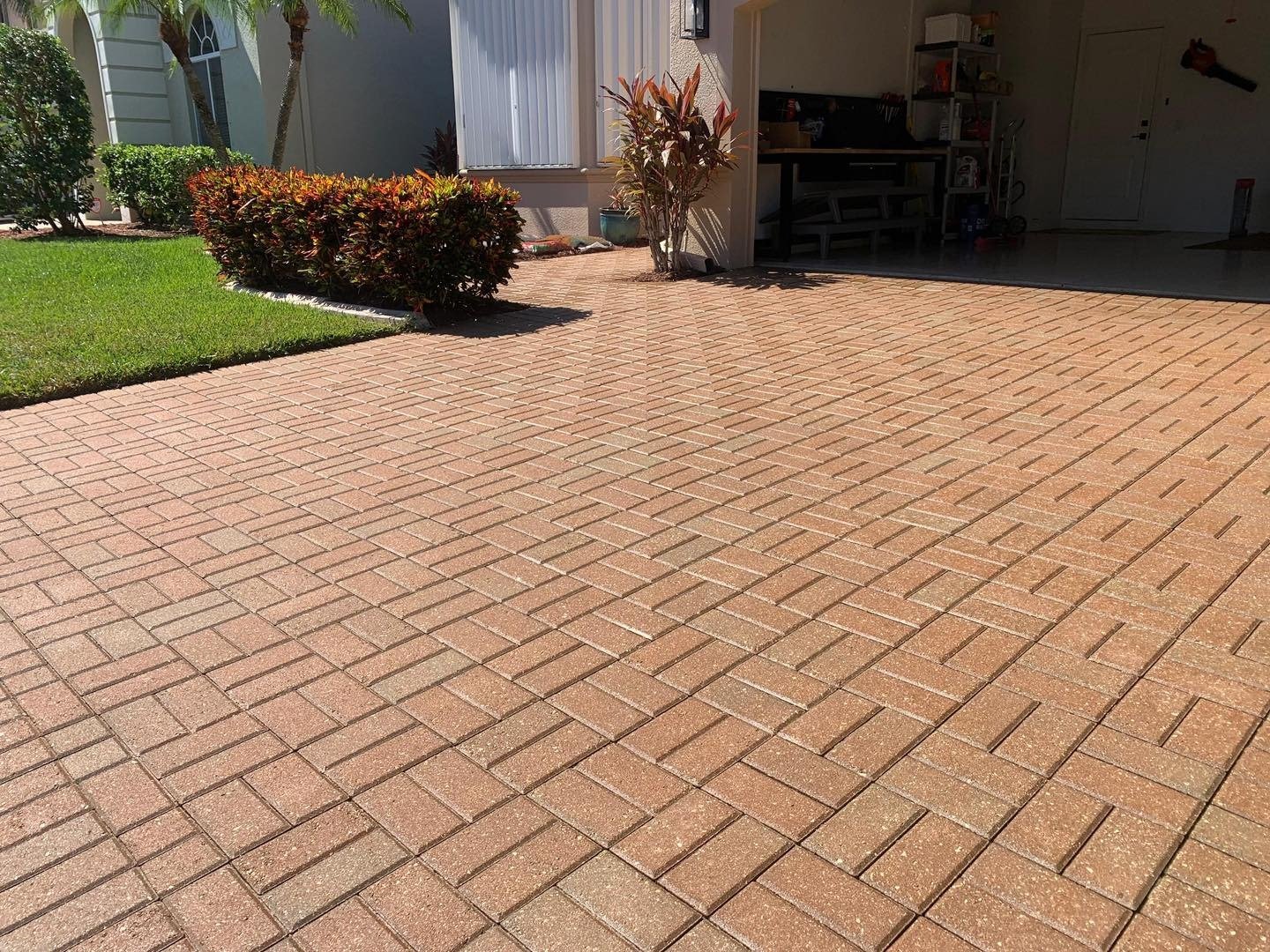 Reddish herringbone paver driveway leading into an open residential garage