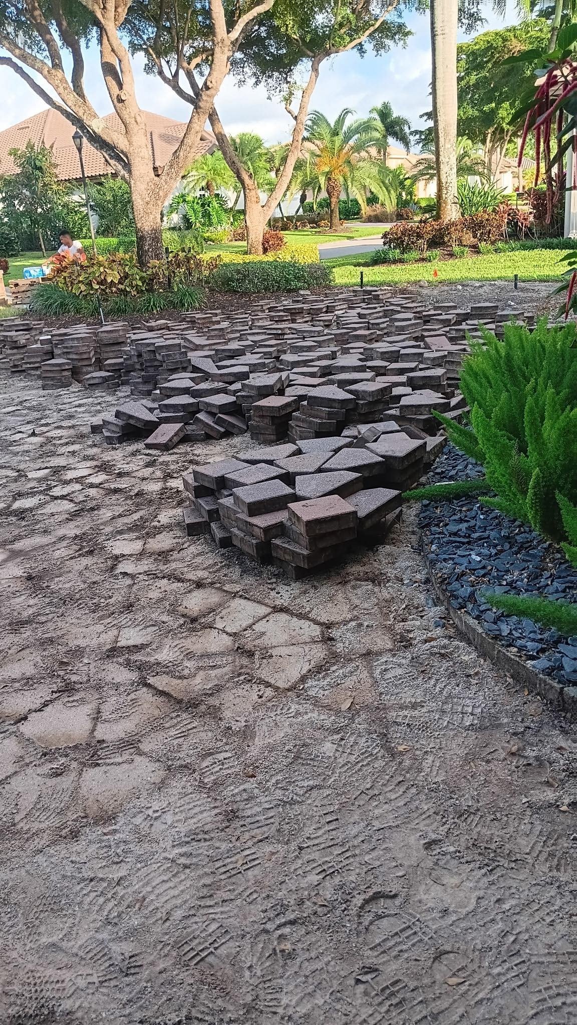 Piles of removed driveway pavers beside a planted garden bed